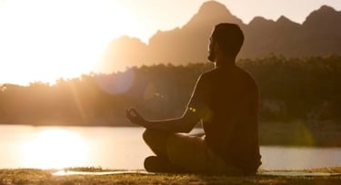 Homme méditant devant un couché de soleil évoquant les problématiques liés à la qualité de vie