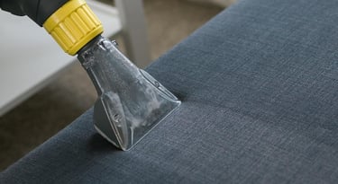 a person using a vacuum cleaner to clean a couch