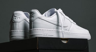 Zapatillas Nike Air Force 1 blancas de cuero de caña baja sobre cajas de zapatos negras.