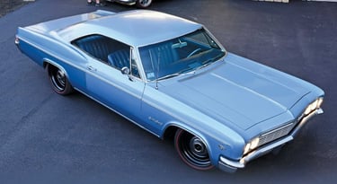 A classic 1966 light blue Chevrolet Impala SS hardtop parked on asphalt with redline tires.