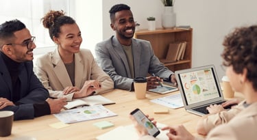 Diverse business team collaborating in a bright office meeting while analyzing data on a laptop.