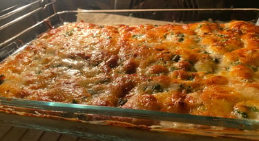 Golden brown cheesy lasagna with bubbling mozzarella baking inside a glass dish in a convection oven.