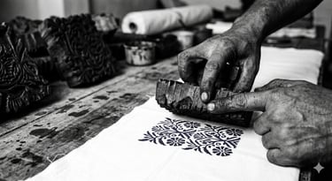 Block print clothing manufacturer India — master artisan hand printing indigo pattern on cotton fabric in Jaipur workshop