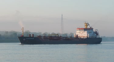Sun shines on a blue and white tanker ship as it passes by.