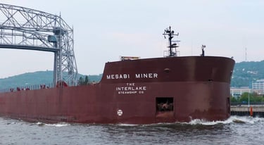 The bow section of the huge red ship Mesabi Miner passing through a narrow canal.