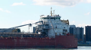 A close-up view of the aft section of a large red ship with a white superstructure.