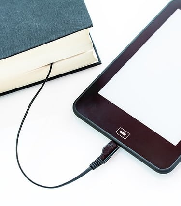 An iPad is connected to a hardbound book with USB cable from the iPad to the hardbound book.
