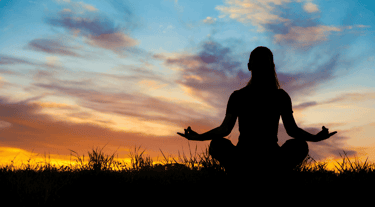 a woman meditating at sunrise