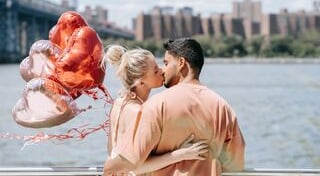 a man and woman kissing on a bridge over a river
