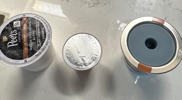 Three different coffee pods including a Peet's K-Cup and espresso capsules on a countertop.