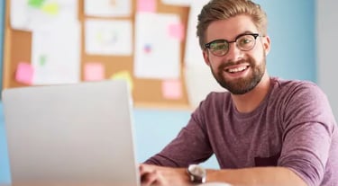En glad man läser en distanskurs online via sin dator.