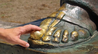 Close-up of a hand touching the golden toe of the Grgur Ninski statue in Split for good luck