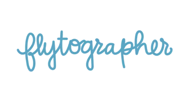 Flytographer brand logo in blue cursive script typography against a solid black background.