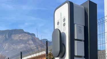 a parking meter with a car parked in front of a fence