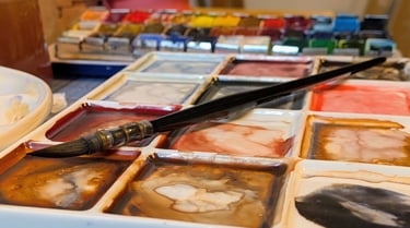 Waterverf palet met penseel en aquarel napjes, gemengde kleuren op een bord