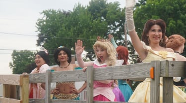 Princesses riding in a parade and waving