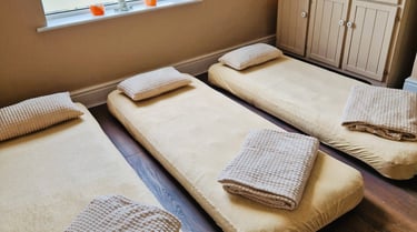 Three air beds on the floor with blankets and pillows
