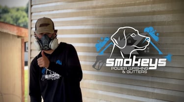 Owner of Smokey’s Power Washing holding a thumbs up with business logo to his right