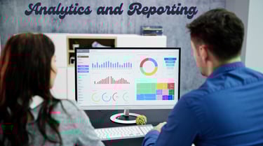 a man and woman sitting at a desk with a computer monitor analytics and reporting on the screen