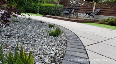 Patio with custom stone circle with aggregates and paving weaving through adventurous garden design
