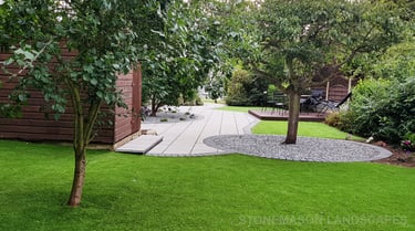 Patio with custom stone circle with aggregates and paving weaving through adventurous garden design