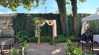 a wedding ceremony with a wooden arch decorated with flowers