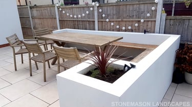 Modern chic raised porcelain patio with white rendered walls and planters