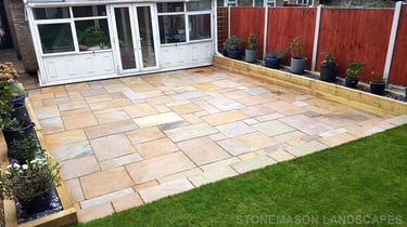 Large sandstone patio and raised wooden sleeper planters