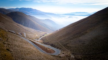 a winding road in the mountains with a view of the mountains