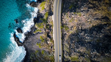 a car driving down a road next to a body of water