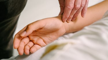 A healthcare provider checking a patient's pulse on their wrist during a medical examination.