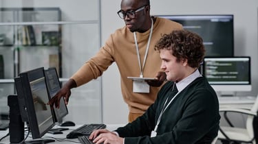 Two diverse IT professionals collaborating on software development at a modern office workstation.