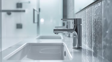 Modern chrome bathroom faucet mounted on a white ceramic sink in a clean, minimalist interior.
