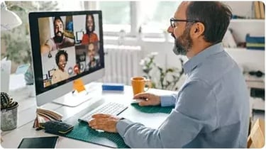 Professional man in a home office having a video conference call with diverse colleagues.