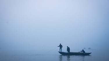 A man in a boat on a foggy day in Varanasi
