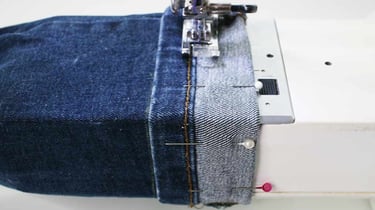 jeans being hemmed on a sewing machine