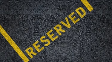Yellow painted reserved sign on black asphalt surface of a parking lot space.