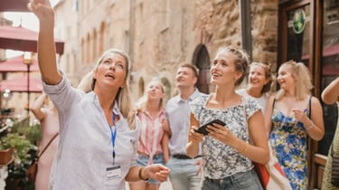 Professional tour guide pointing at architecture for a group of tourists on a walking tour in Europe.