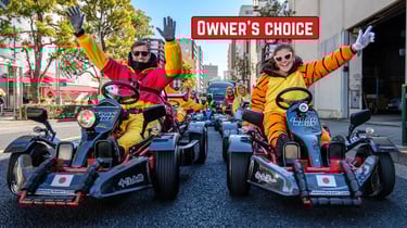 A couple wearing character-style costumes driving a street go-kart together in Japan