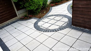 Patio with custom stone circle with aggregates and paving weaving through adventurous garden design
