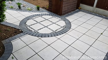 Patio with custom stone circle with aggregates and paving weaving through adventurous garden design
