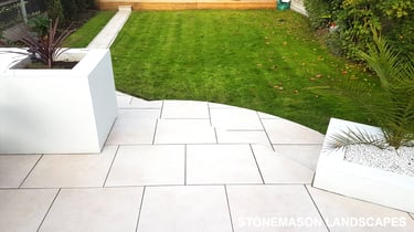 Modern chic raised porcelain patio with white rendered walls and planters
