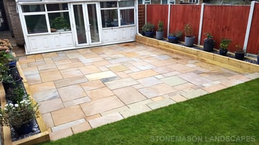 Large sandstone patio and raised wooden sleeper planters