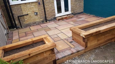 Colourful sandstone patio with raised wooden timber planter seating