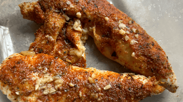 Baked Chicken Broil sample image cooked with glazed spices ontop and garlic slices.