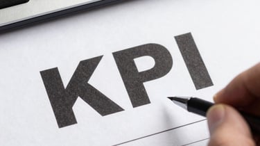 A person pointing a pen at the KPI text on a business report next to a computer keyboard.