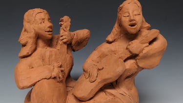 a clay sculpture of a woman playing guitar