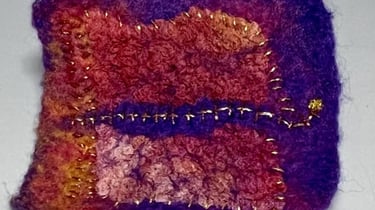 a small square shaped object with a purple and gold colored design