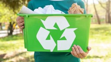 Una persona tiene in mano un bidone verde per la raccolta differenziata