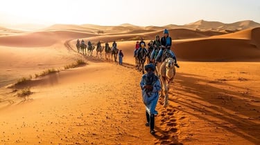 a group of people riding camels in the desert